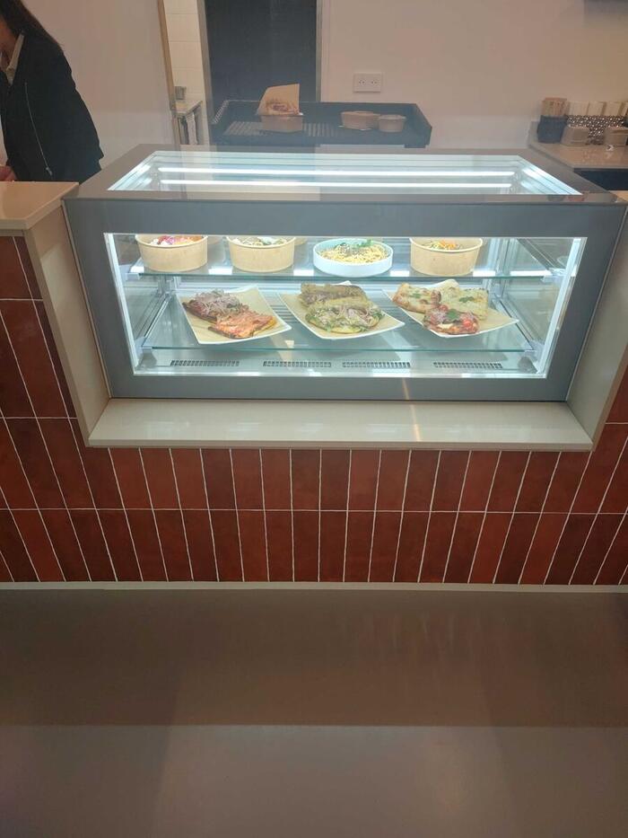 Le comptoir revêtu de carreaux rouge brique et sa vitrine éclairée