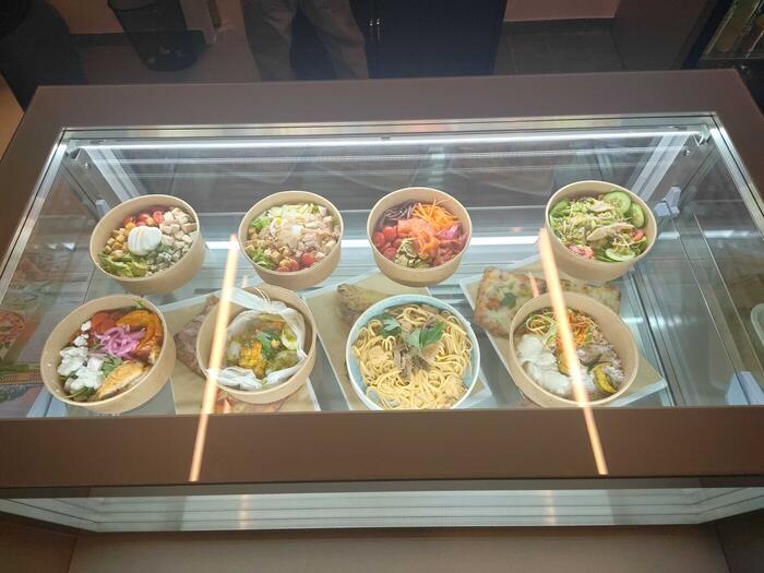 La vitrine vue du dessus : salades en boîtes kraft, pâtes, pizzas et sandwichs