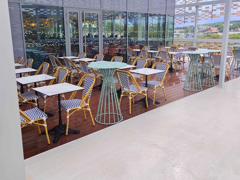 La terrasse : chaises en rotin à chevrons bleus et blancs, tables en marbre, mange-debout vert d'eau